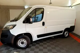 Vue latérale gauche d’un FIAT Ducato Fourgon blanc 2021 avec jantes acier et rétroviseurs noirs dans un garage.