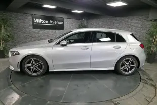 Profil côté gauche d'une Mercedes Classe A 200 d AMG Line gris métallisé avec jantes AMG 18 pouces en intérieur showroom.
