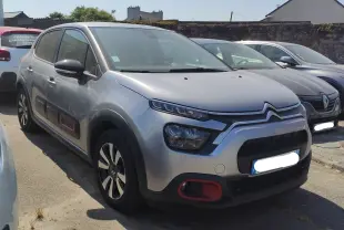 Citroën C3 gris Artense métal vue 3/4 avant droit avec inserts rouges sur bouclier et protections latérales.
