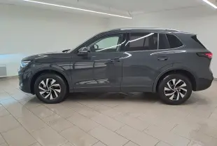 Vue de profil côté gauche du Volkswagen Tiguan 2024 gris Urano avec jantes distinctives et attelage escamotable visible.