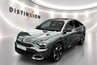 Citroën C4 gris 3/4 avant droit, avec jantes noires et toit panoramique en showroom lumineux.