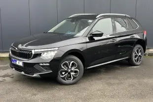 Vue 3/4 avant droite d'un Skoda Kamiq noir Magic avec jantes alliage et baguettes chromées sur fond urbain.