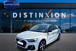 Audi A1 Sportback blanc et noir vue 3/4 avant droit devant une vitrine Distinxion, jantes alu et toit noir contrasté.