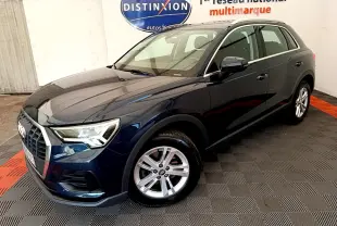 Audi Q3 bleu foncé vu en 3/4 avant droit dans un showroom avec jantes alliage et feux LED allumés.