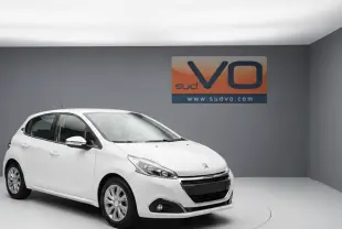 Peugeot 208 blanc vue 3/4 avant gauche dans un studio avec jantes classiques et phares antibrouillard visibles.