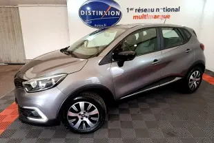 Renault Captur Business gris foncé vu de profil côté gauche dans un showroom avec logo Distinxion en arrière-plan.