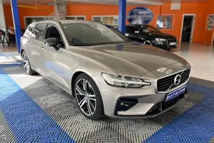 Volvo V60 gris en 3/4 avant droit, avec jantes alliage et calandre distinctive en intérieur showroom.