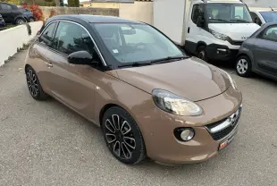 Opel Adam marron vue 3/4 avant droit, toit noir, jantes alliage 16 pouces et phares allumés sur parking.