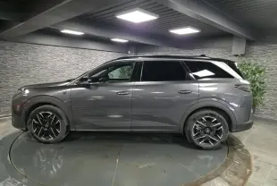 Vue de profil côté gauche d’un Peugeot 5008 gris métallisé avec jantes alliage noires dans un showroom intérieur.