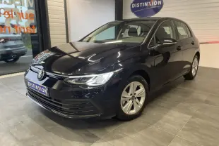 Volkswagen Golf 1.5 eTSI noire vue 3/4 avant en intérieur avec jantes alliage et logo lumineux sur calandre.