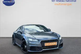 Audi TT Coupé gris métallisé en 3/4 avant avec jantes noires et plaque orange "OCCASION" visible sur un fond neutre.