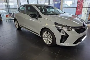 Renault Clio V gris Rafale vue 3/4 avant droit en intérieur, avec phares LED et rétroviseurs noirs brillants.