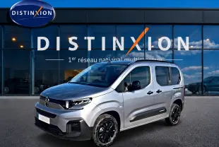 Citroën Berlingo Steel Grey en 3/4 avant droit, avec jantes noires et barres de toit visibles devant showroom Distinxion.