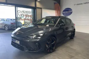 Vue 3/4 avant d'une CUPRA Leon gris magnetic avec jantes cuivrées et toit ouvrant panoramique en showroom.