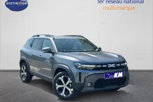 Vue 3/4 avant d'un Dacia Duster gris avec jantes alu et barres de toit sur fond neutre.
