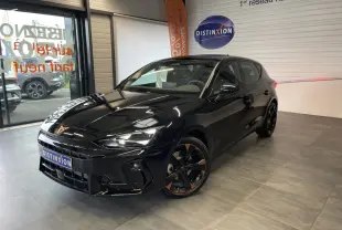 Vue 3/4 avant droite d'une CUPRA Leon noire avec jantes alliage noires et cuivrées, dans un showroom intérieur.