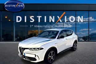 Vue 3/4 avant d'une Alfa Romeo Tonale blanche avec jantes alu distinctives, stationnée devant une vitrine Distinxion.