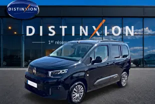 Citroën Berlingo noir vue 3/4 avant droit, avec barres de toit et jantes alu devant showroom Distinxion.