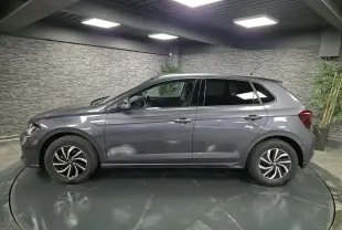 Volkswagen Polo gris métallisé vue de profil côté gauche avec jantes alliage et vitres arrière surteintées.