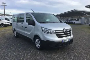 Renault Trafic Combi gris clair métal vu en 3/4 avant droit sur un parking avec plusieurs autres véhicules utilitaires.