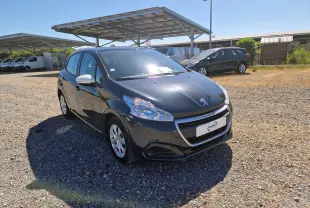 Peugeot 208 gris hurricane vue 3/4 avant droit sur parking, avec rétroviseurs blancs et jantes alliage.