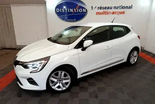 Renault Clio Business blanche vue de côté droit en intérieur, avec feux avant allumés et jantes alliage.