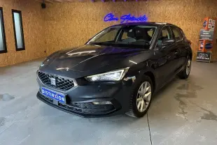 SEAT Leon gris 2021 en 3/4 avant droit dans un showroom avec éclairage intérieur et mur en bois.