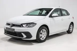 Volkswagen Polo blanche vue en 3/4 avant droit, avec phares allumés et jantes acier à enjoliveurs.