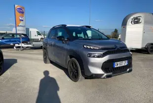 Vue 3/4 avant droit d'un Citroën C3 Aircross 2024 gris foncé avec jantes noires, stationné en extérieur au soleil.