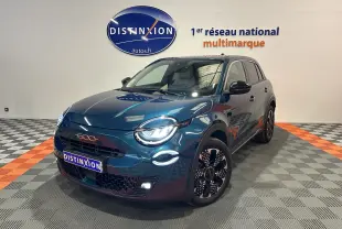 Vue 3/4 avant droite d'une FIAT 600 Hybrid 100 La Prima bleu métallisé avec phares LED allumés en showroom