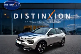 Citroën C4 1.5 BlueHDi 130 gris vue 3/4 avant droit, avec jantes alu et phares LED devant un showroom Distinxion.