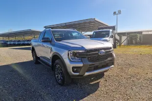 Vue 3/4 avant droite d'un Ford Ranger Super Cabine gris Iconic avec calandre noire et jantes alliage, stationné en extérieur.