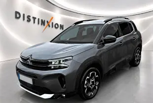 Citroën C5 Aircross gris vue 3/4 avant droit avec barres de toit et jantes alu distinctives.
