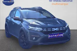 Vue 3/4 avant d'une Dacia Sandero Stepway 2025 en kaki lichen avec jantes noires et barres de toit.
