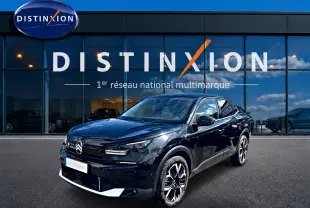 Citroën C4 X noir en 3/4 avant droit, avec jantes alu et calandre distinctive, devant une vitrine Distinxion.