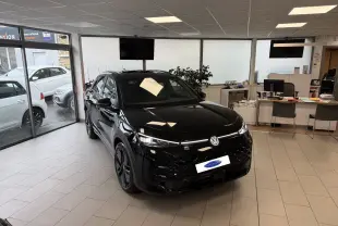 Volkswagen T-Roc Noir Intense en vue 3/4 avant droit dans un showroom avec jantes noires et calandre R-Line.