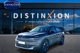 Citroën C4 X gris mercure en 3/4 avant droit, avec calandre épurée et jantes alu noires devant showroom Distinxion.
