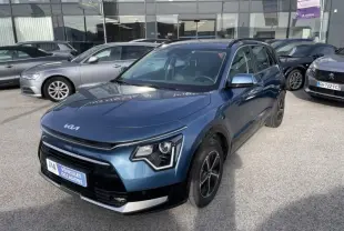 KIA Niro 2024 bleu métal en vue 3/4 avant droit, avec signature lumineuse distinctive et jantes noires.