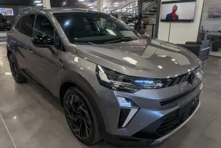 Renault Symbioz E-Tech gris Cassiopé en 3/4 avant droit, avec jantes noires et éclairage LED distinctif.