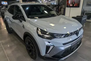 Vue 3/4 avant droite d'une Renault SYMBIOZ E-TECH Full Hybrid gris Rafale avec jantes noires en showroom.