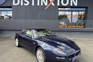 Maserati Coupé 4200 GT bleu vue 3/4 avant droit, jantes alliage et intérieur clair visibles.