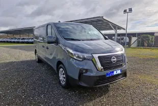 Vue 3/4 avant d’un Nissan Primastar gris urbain 2025 avec calandre chromée et plaque "Zero KM" visible.