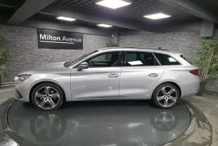 Profil droit d'un break SEAT Leon Sportstourer gris urbain 2022 avec jantes alliage 18 pouces dans un showroom.