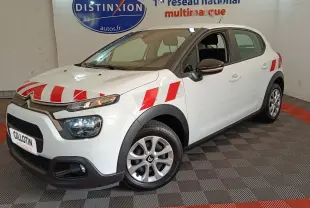 Vue 3/4 avant gauche d'une Citroën C3 blanche avec bandes rouges distinctives sur capot et ailes, en intérieur showroom.