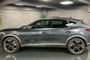 Profil côté gauche d'un CUPRA Formentor gris magnétique 2023 avec jantes alliage 19 pouces et prises de recharge visibles.