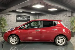 Profil côté gauche d'une Nissan Leaf 30 Visia rouge métallisée, soulignant ses jantes blanches et la mention zéro émission.