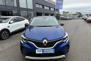 Vue frontale d'un Renault Captur E-Tech 145 Zen bleu métal 2022 avec logo Renault et plaque "Véhicules Occasions" visible.