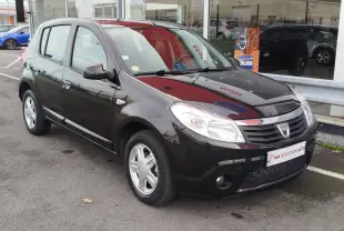 Dacia Sandero noire vue en 3/4 avant droit, avec calandre chromée et jantes alliage 15 pouces visibles.
