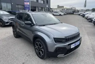 Jeep Avenger gris métal en vue 3/4 avant droit, avec calandre distinctive et jantes noires à motifs argentés.