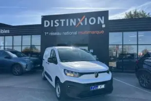 Vue 3/4 avant d'un utilitaire Citroën Berlingo blanc Icy avec pare-chocs noir devant un bâtiment Distinxion.